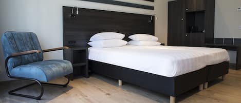 Un dormitorio moderno con cama, una silla, una mesita de noche y un armario.