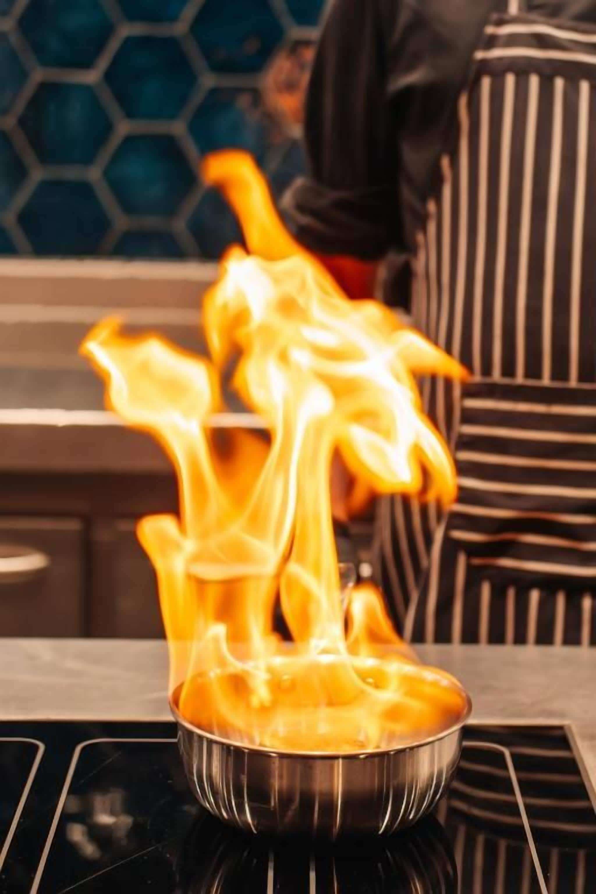 Un récipient en métal sur une cuisinière, avec des flammes.