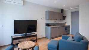 A modern living room with a flat-screen TV, a wooden coffee table, and two blue sofas. - Hotel De Naaldhof (Oss)