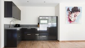 A modern kitchen with black cabinets, a stainless steel refrigerator, and a coffee maker. - Hotel De Naaldhof (Oss)