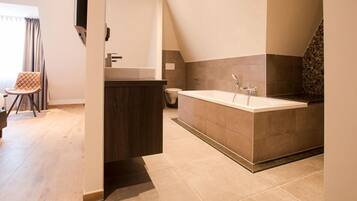 A modern bathroom with a freestanding bathtub, a vanity with a mirror, and a toilet.