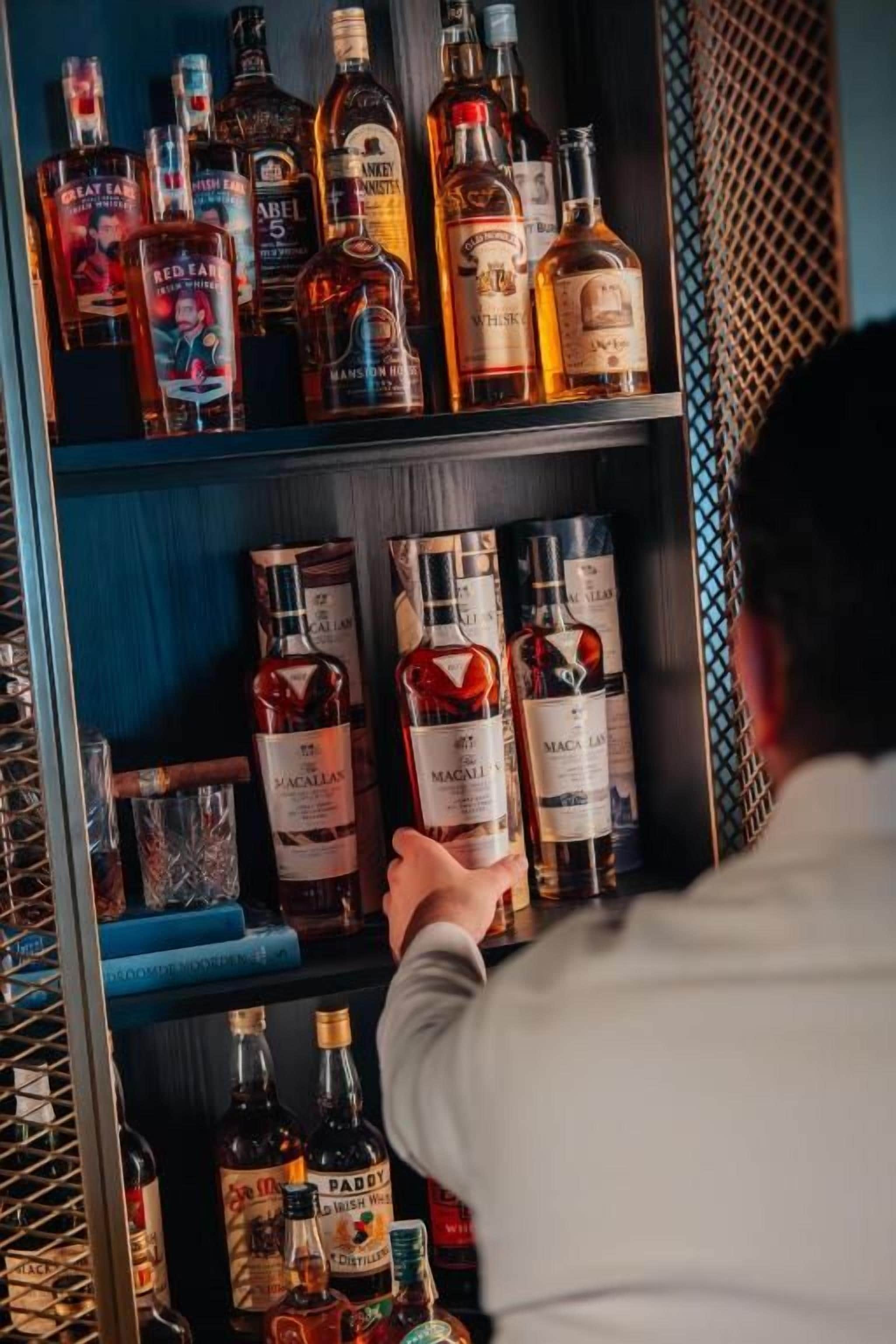 Una persona observando una estantería con diferentes botellas de licor.