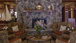 Un vestíbulo con chimenea de piedra, muebles de mimbre y un candelabro.