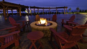 Un espacio al aire libre con una chimenea, sillas y mesas.