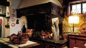 Una cocina rústica con utensilios de cobre, una mesa de madera y una pared de piedra.