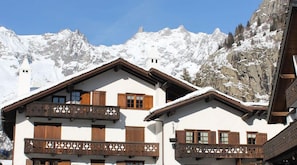 A chalet with wooden balconies, white walls, and a mountain backdrop. - Hotel del Viale (Courmayeur)