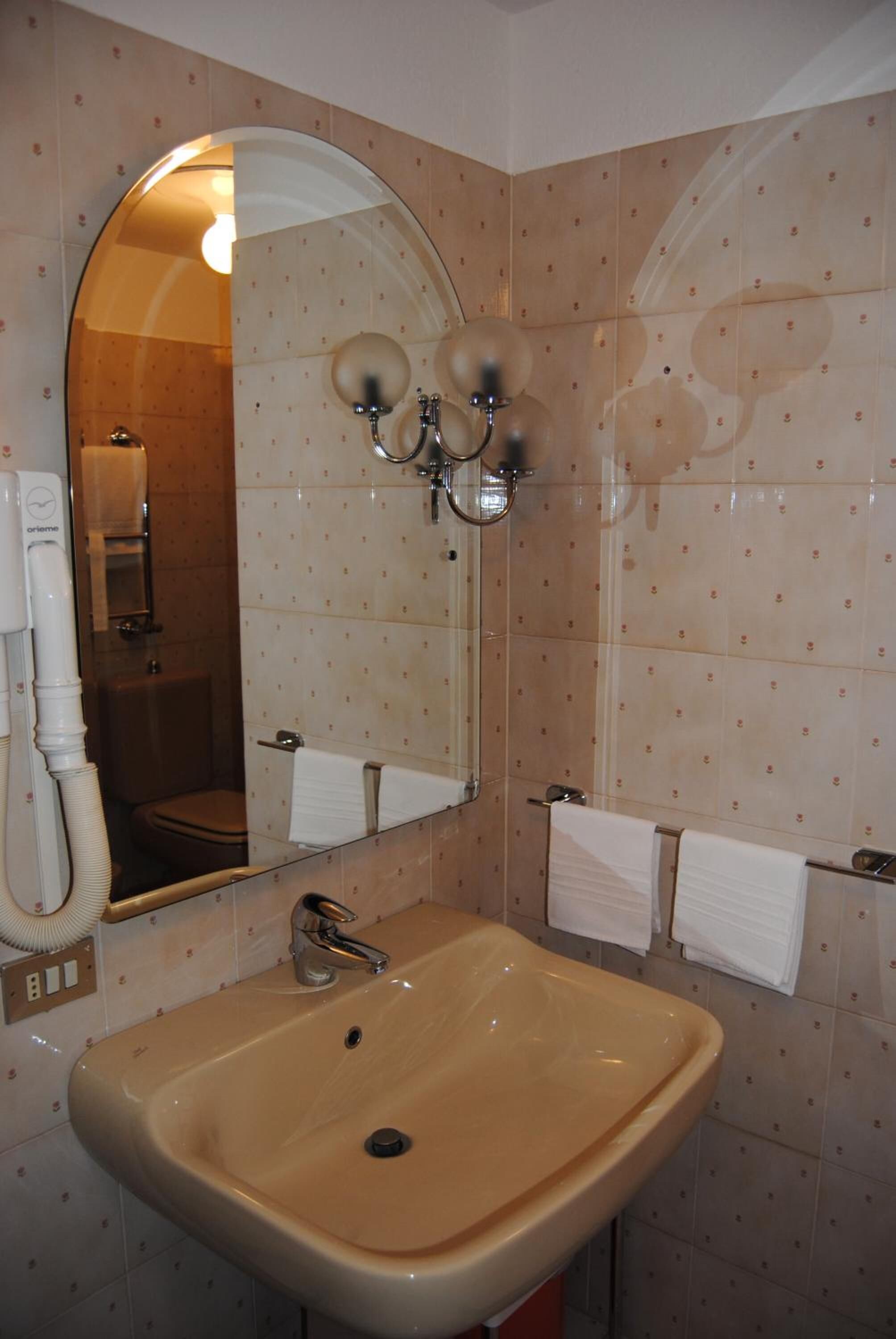 Un baño con lavamanos, espejo y perchero para toallas.
