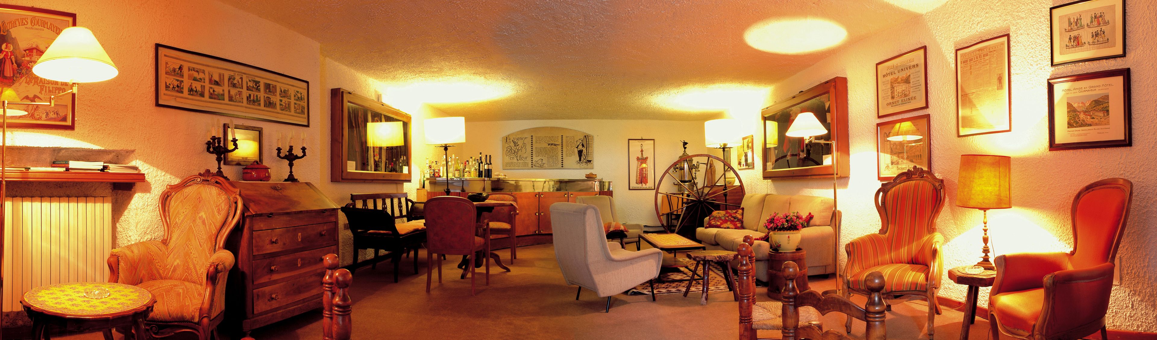 Un hall de hotel cálidamente iluminado con decoración tradicional, que incluye muebles antiguos y cuadros enmarcados en las paredes.