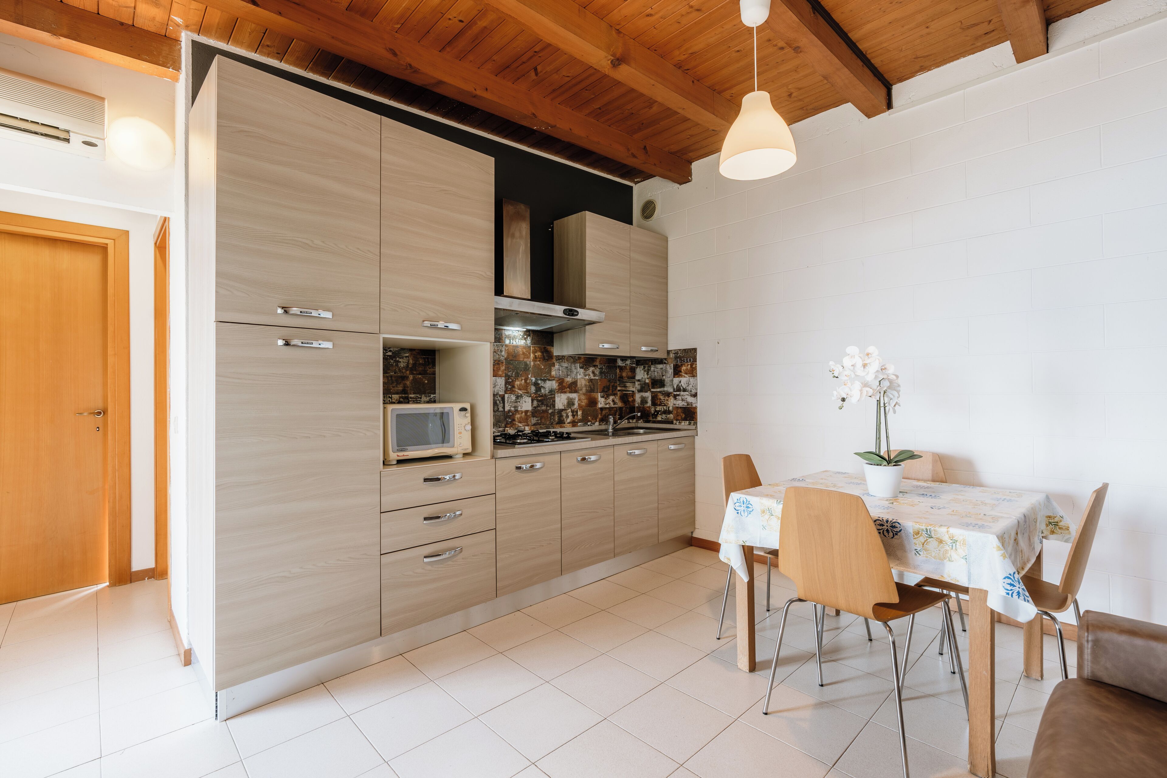 Une cuisine moderne avec des meubles en bois, un four à micro-ondes et un coin repas comprenant une table et des chaises.