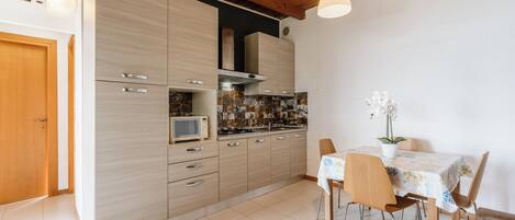 Une cuisine moderne avec des meubles en bois, un four à micro-ondes et un coin repas comprenant une table et des chaises.