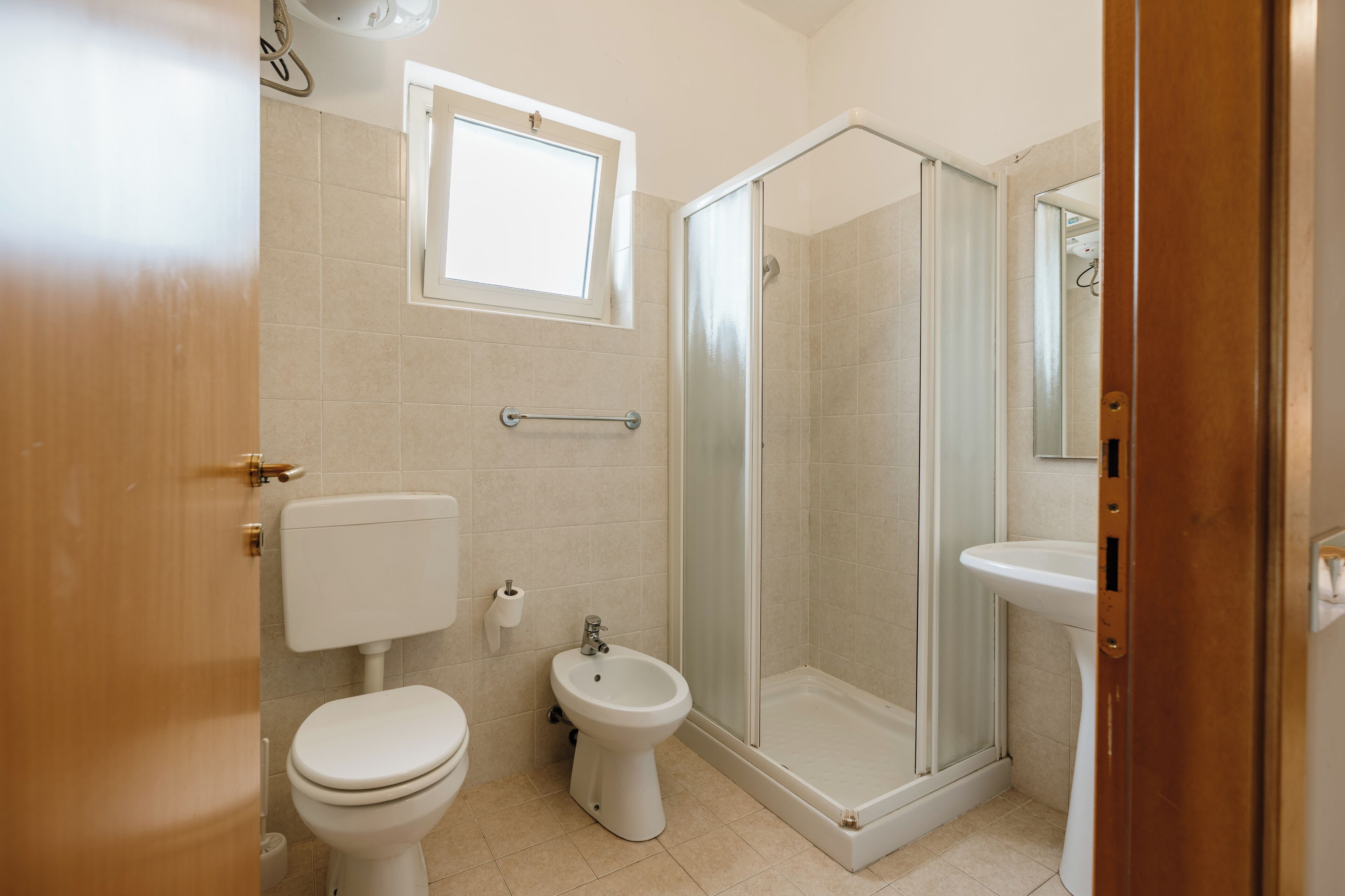 Een badkamer met toilet, bidet en een douche met glazen wanden.