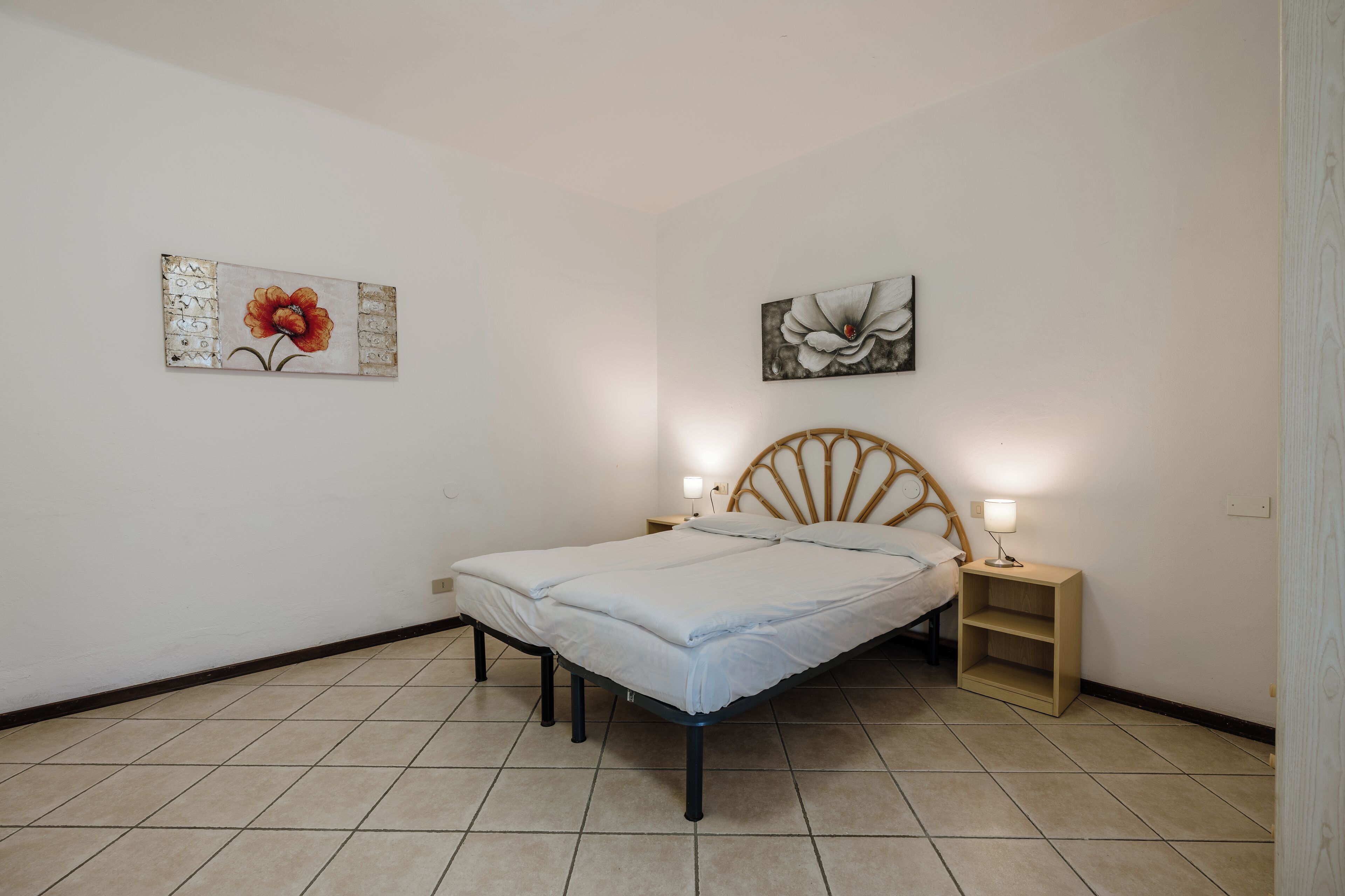 Een slaapkamer met een bed, twee nachtkastjes en decoratie aan de muur.
