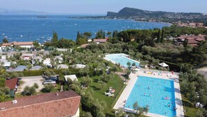 Un resort con una amplia piscina, exuberante vegetación y vistas al mar.