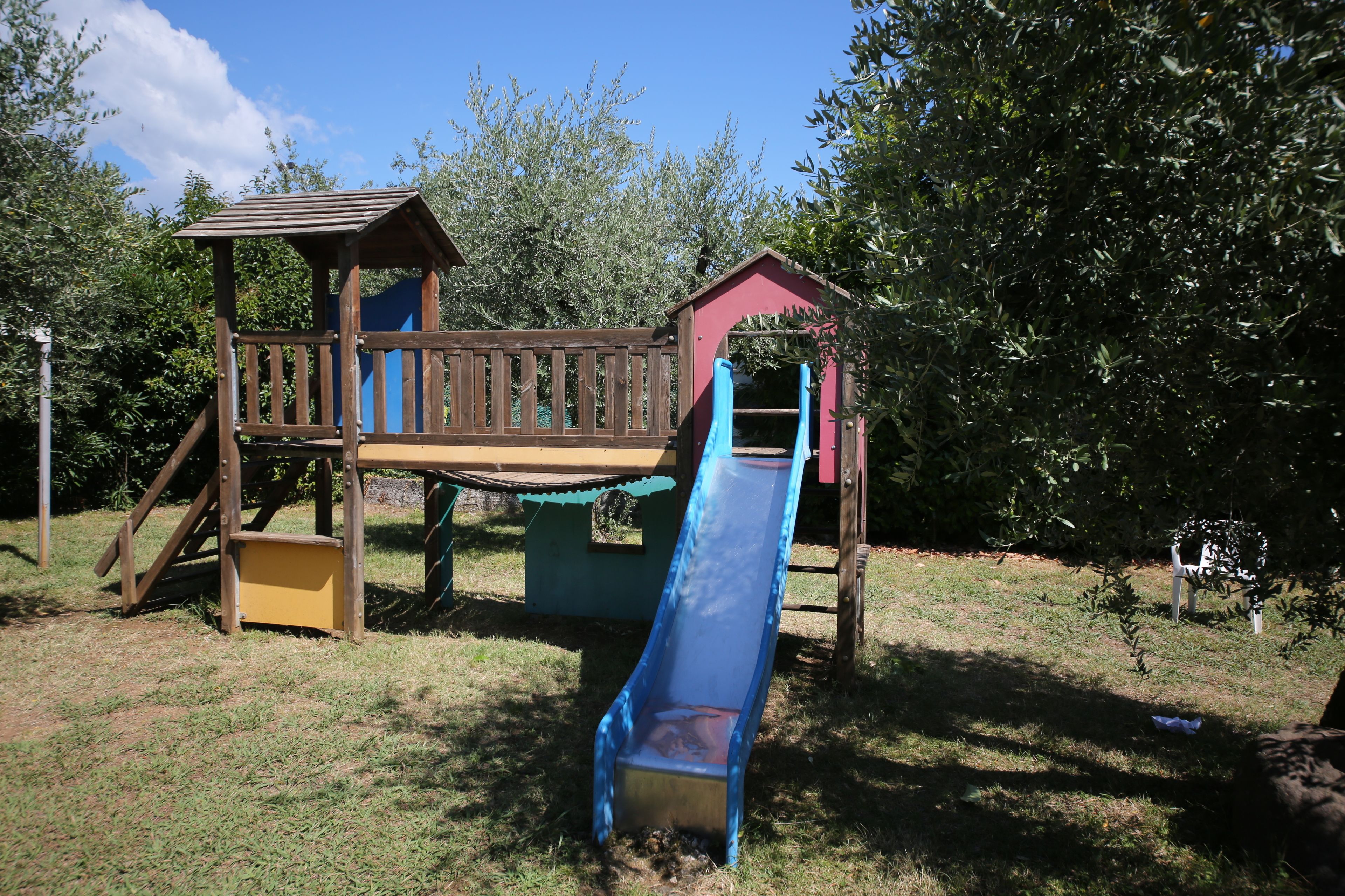 A wooden play structure with a slide and a small shelter.