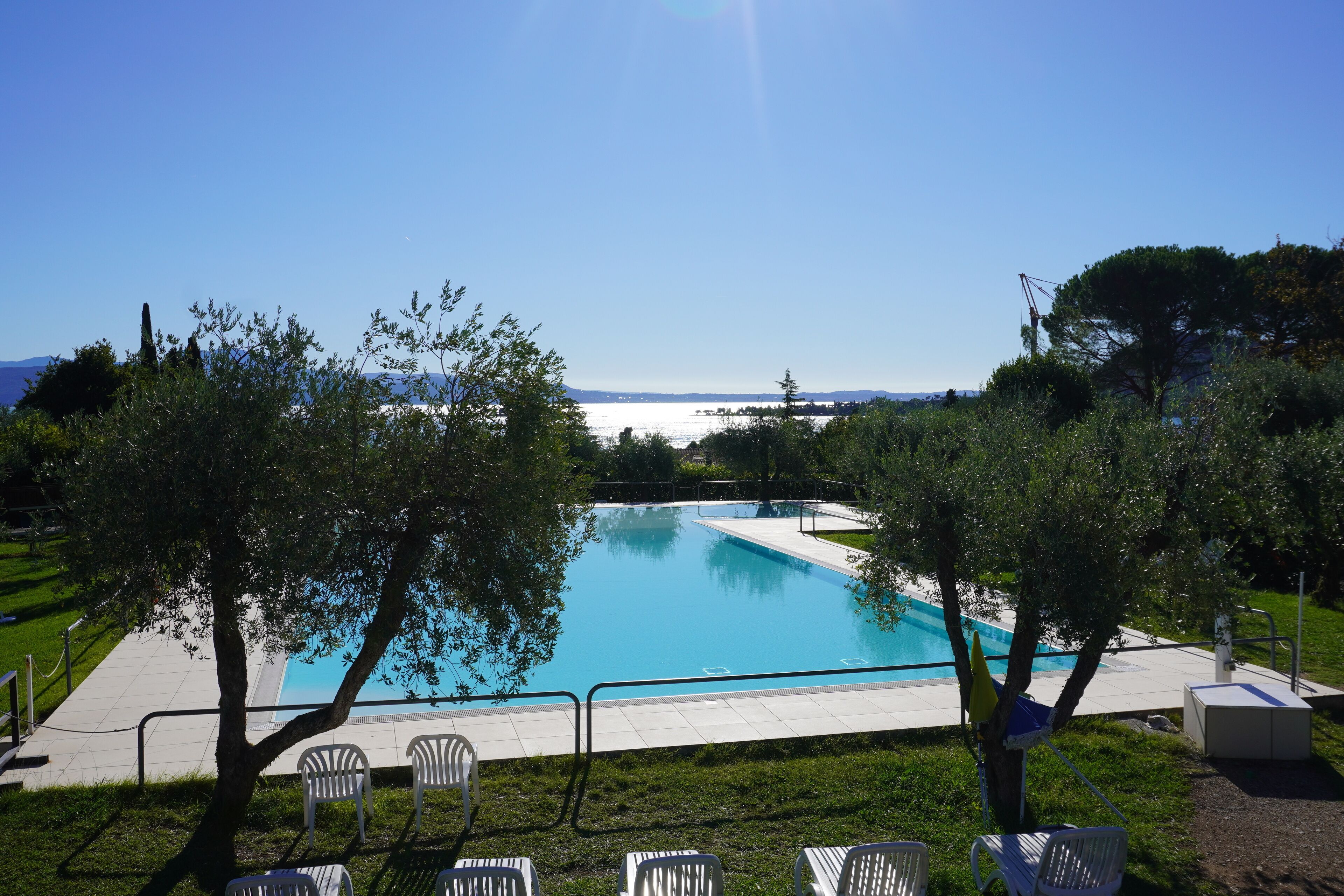A clear blue pool with a view of the sea and mountains in the background.