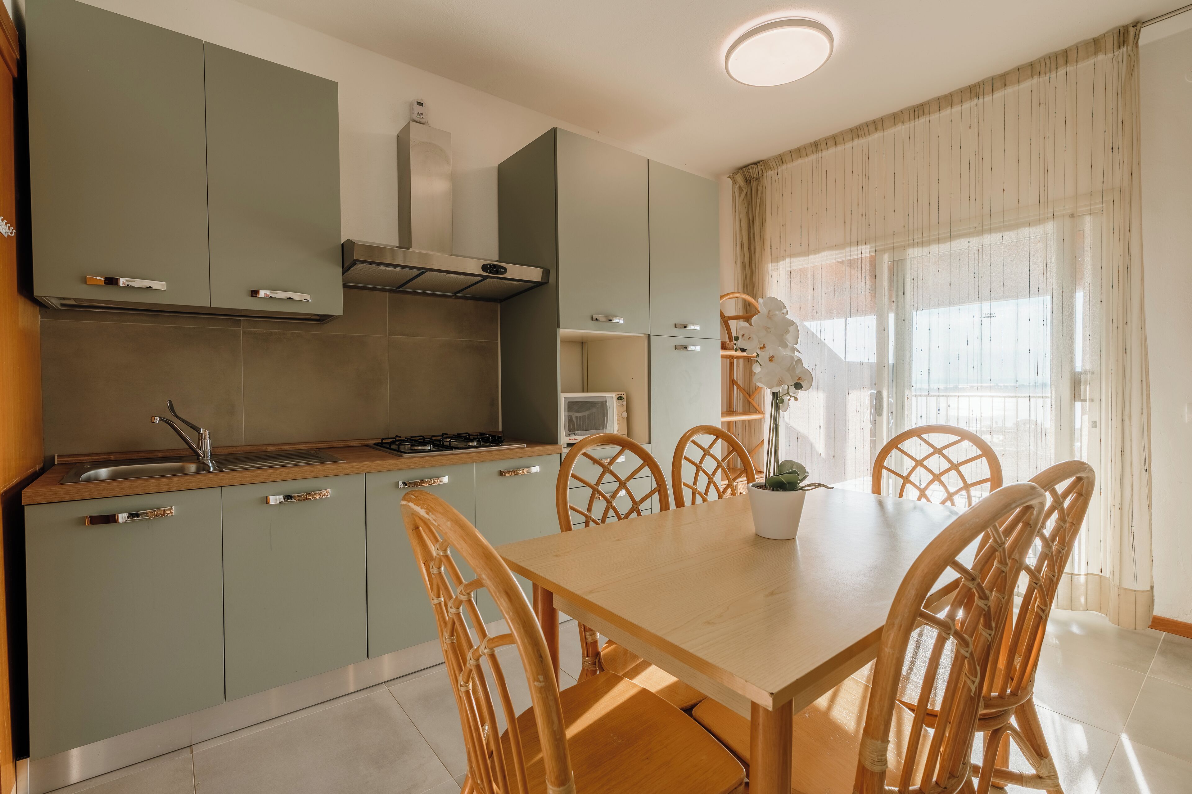 Une cuisine moderne avec des meubles de couleur grise, une table à manger en bois et des chaises en osier.