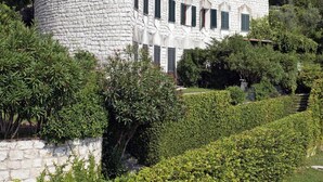 Un edificio de piedra con techo curvo, rodeado de vegetación y árboles.