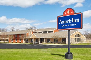 Uma hospedaria americana com uma placa indicando que oferece alojamento e suítes. O edifício tem uma estrutura de dois andares com fachadas de tijolo e pedra.