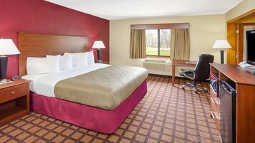 A hotel room with a large bed, a desk with a chair, a television, and a window with curtains.