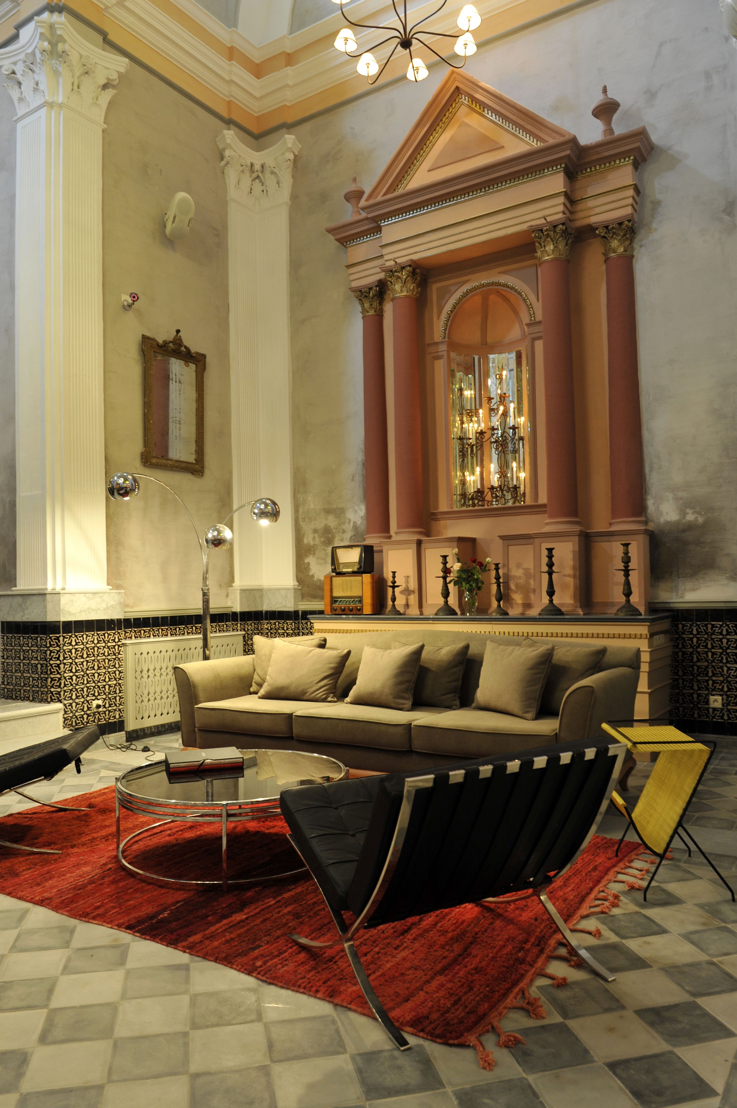 A room with a beige sofa, a red rug, a round coffee table, and a black chair.
