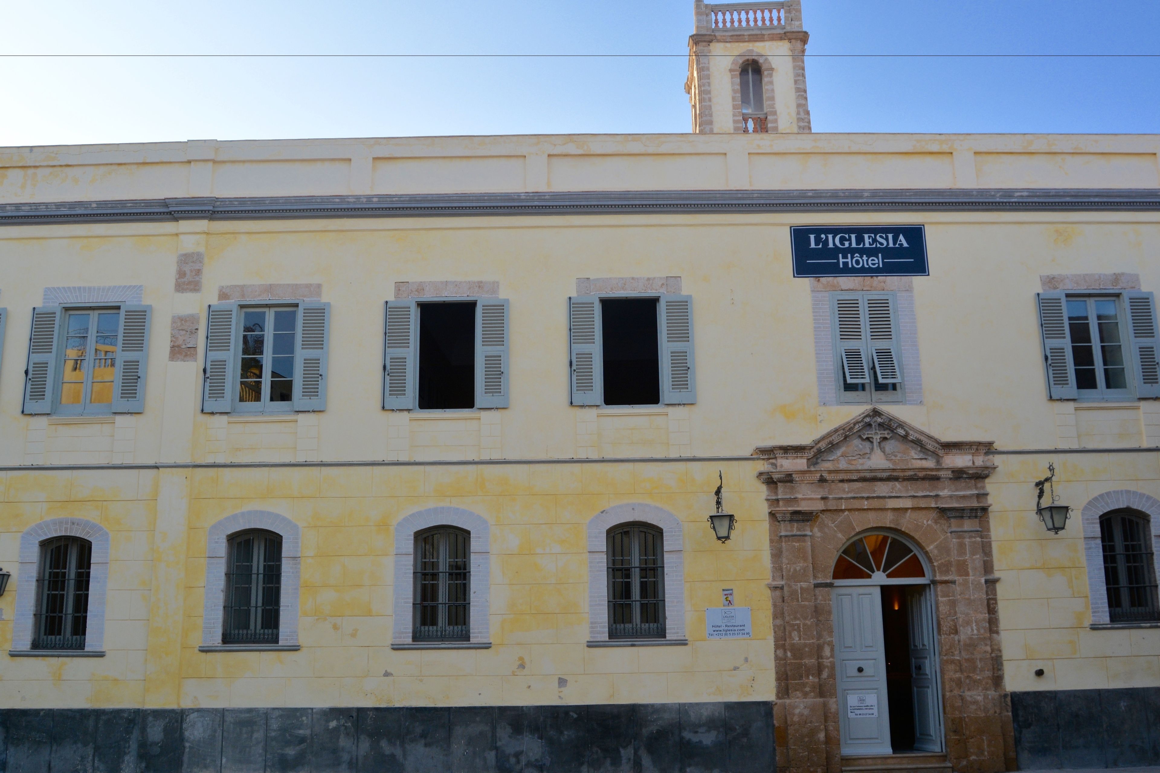 A building with a sign reading "L'IGLESIA Hotel" and a bell tower.