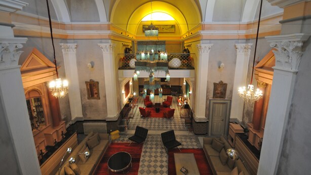 Eine prachtvolle Lobby mit Schachbrettmuster-Boden, roten Sofas und einem Kronleuchter.