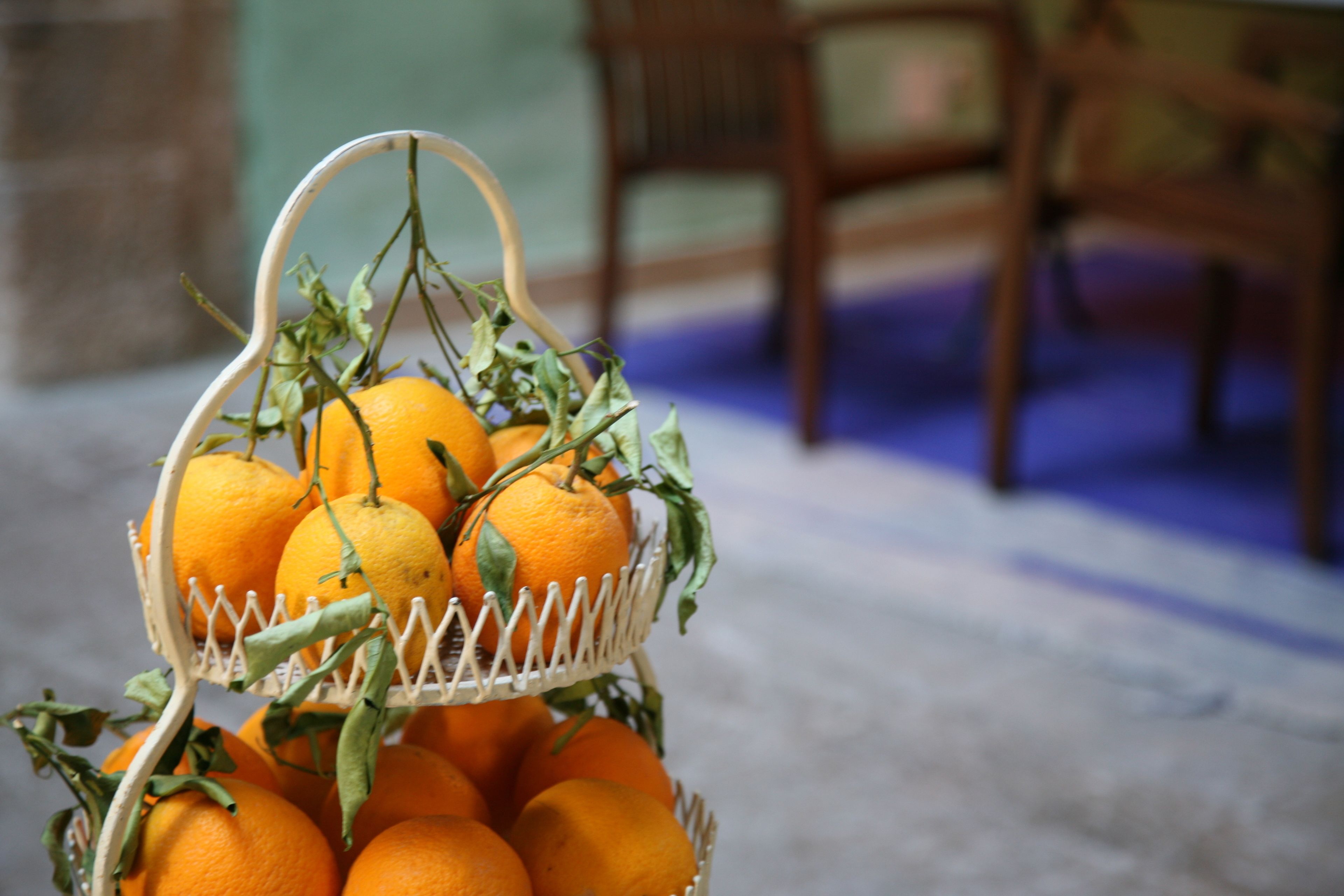 A wicker basket with oranges and leaves.