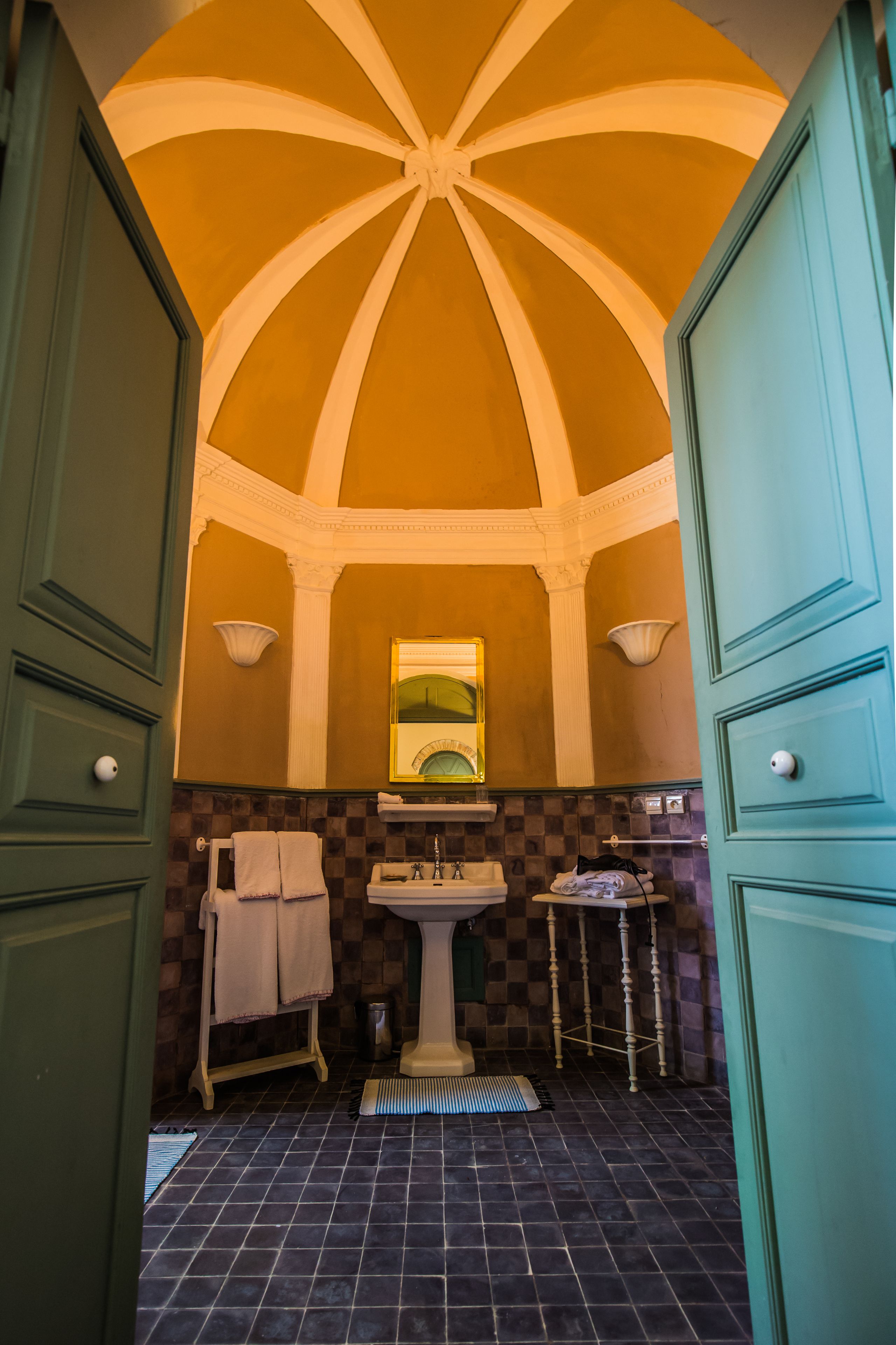 A bathroom with a checkered floor, a pedestal sink, and a mirror with a green frame.