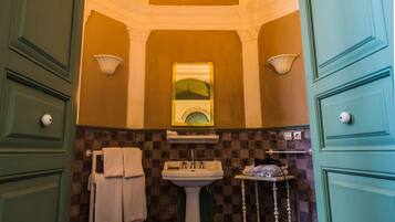 A bathroom with a checkered floor, a pedestal sink, and a mirror with a green frame.