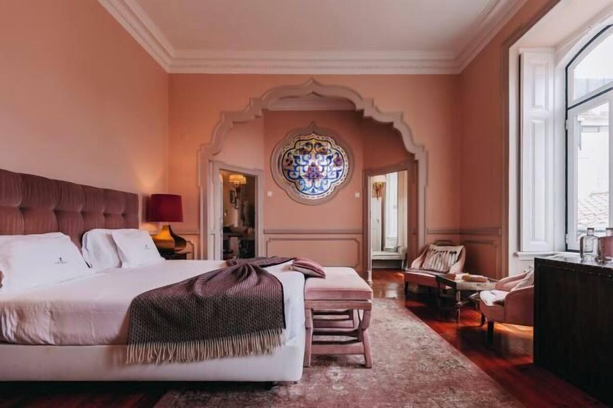 Une chambre à coucher avec un grand lit, un banc, un bureau et un élément décoratif mural.
