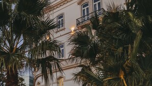 Un edificio con torre, balcones y palmeras.