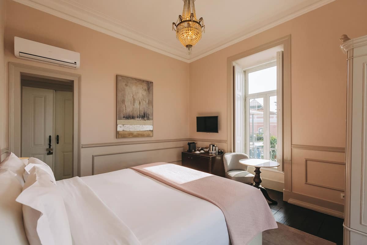 Une chambre d’hôtel avec un grand lit, un bureau avec une chaise, une télévision et une fenêtre donnant sur l’extérieur.