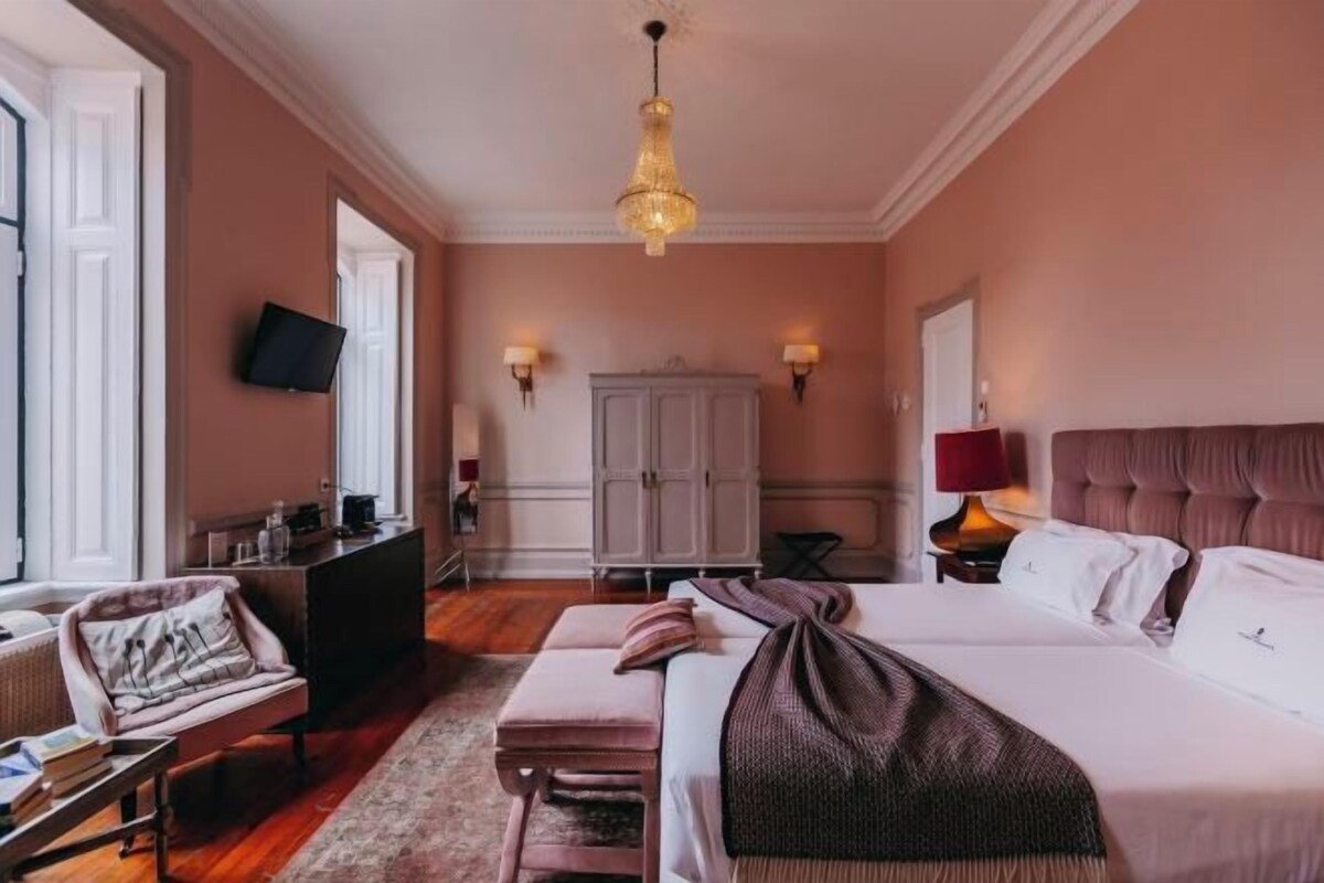 A hotel room with a large bed, a desk, a chair, a wardrobe, and a television.