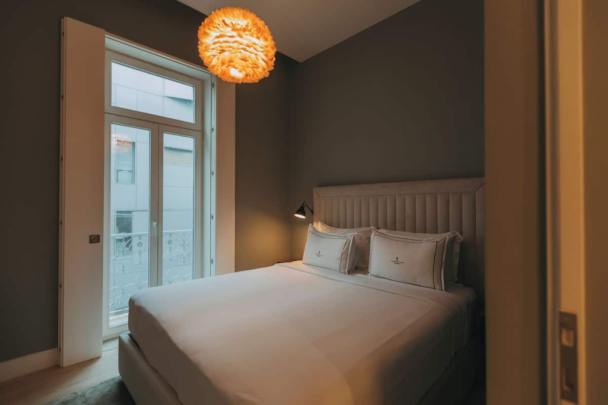 Une chambre à coucher avec un lit, une table de chevet, une fenêtre et une porte.