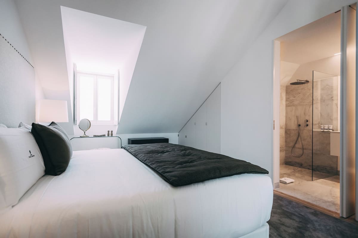 Une chambre moderne avec une lucarne, un lit, une table de chevet et une douche à l’italienne.