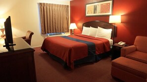 Una habitación de hotel con una cama, un escritorio, una silla, una lámpara y un televisor.
