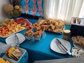 Una mesa de buffet con diversas opciones de comida, como frutas, pasteles y salsas.