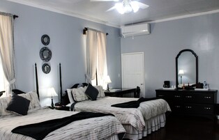 Habitación de hotel con dos camas, un escritorio, una silla, un aparador, un espejo y un aire acondicionado.