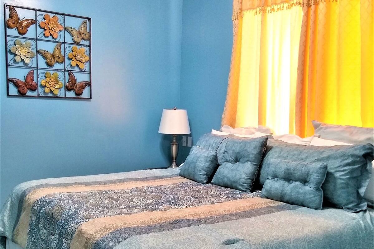 A bedroom with two beds, a nightstand, a lamp, and a wall art piece.