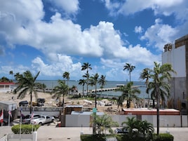 Vista costera con palmeras, una playa y una obra en construcción.