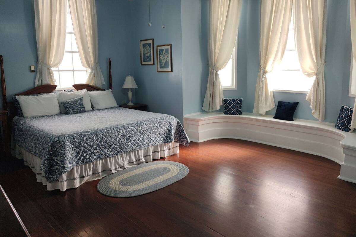 A bedroom with a large bed, a curved bench, and a window seat.