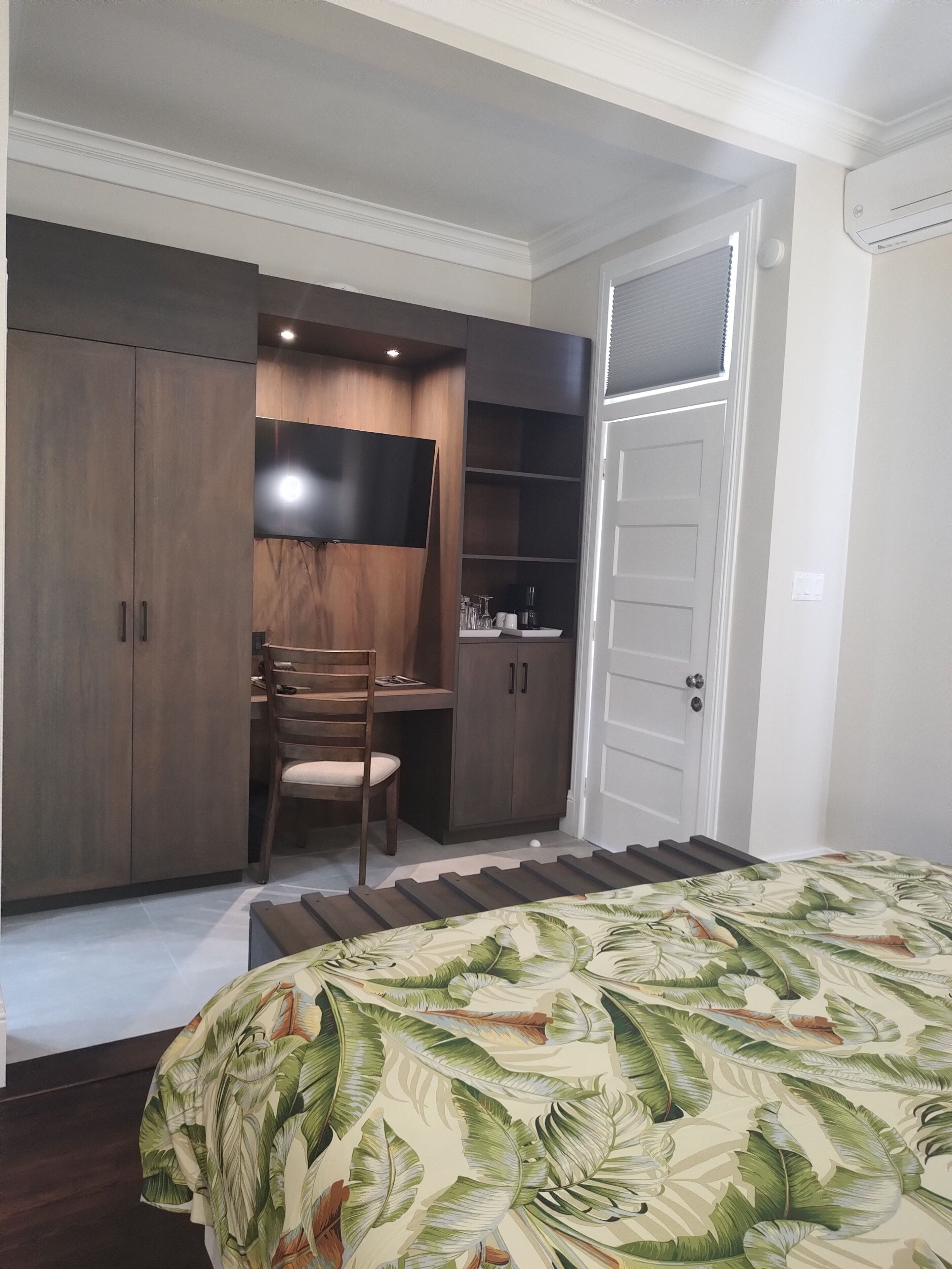 A bedroom with a bed, a desk, and built-in wardrobe.