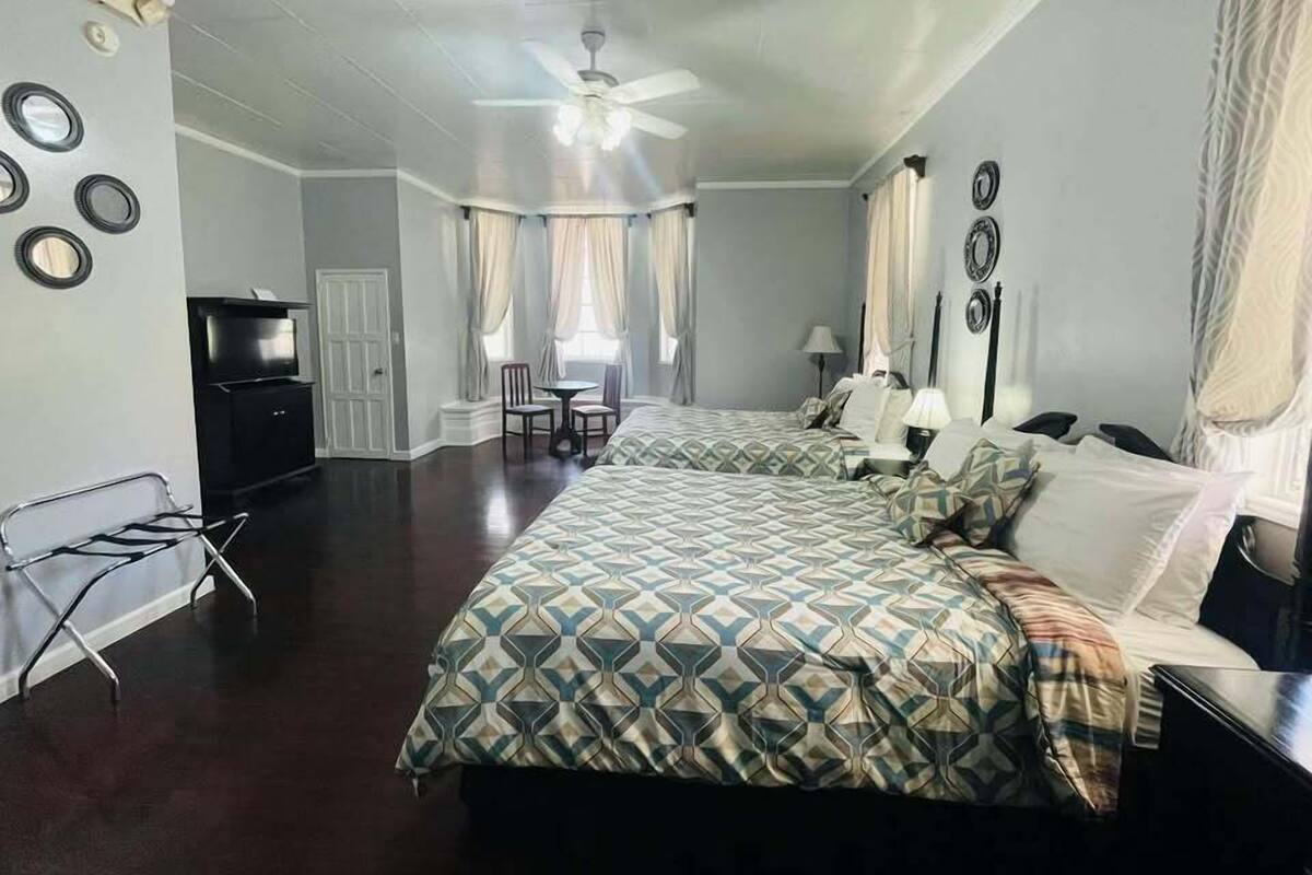 A hotel room with two beds, a TV, a desk, and a chair.