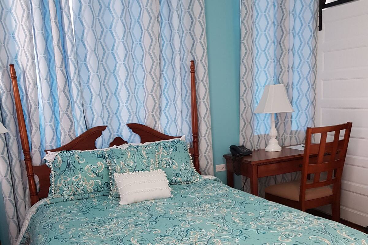 A bedroom with a bed, a desk, and a chair.