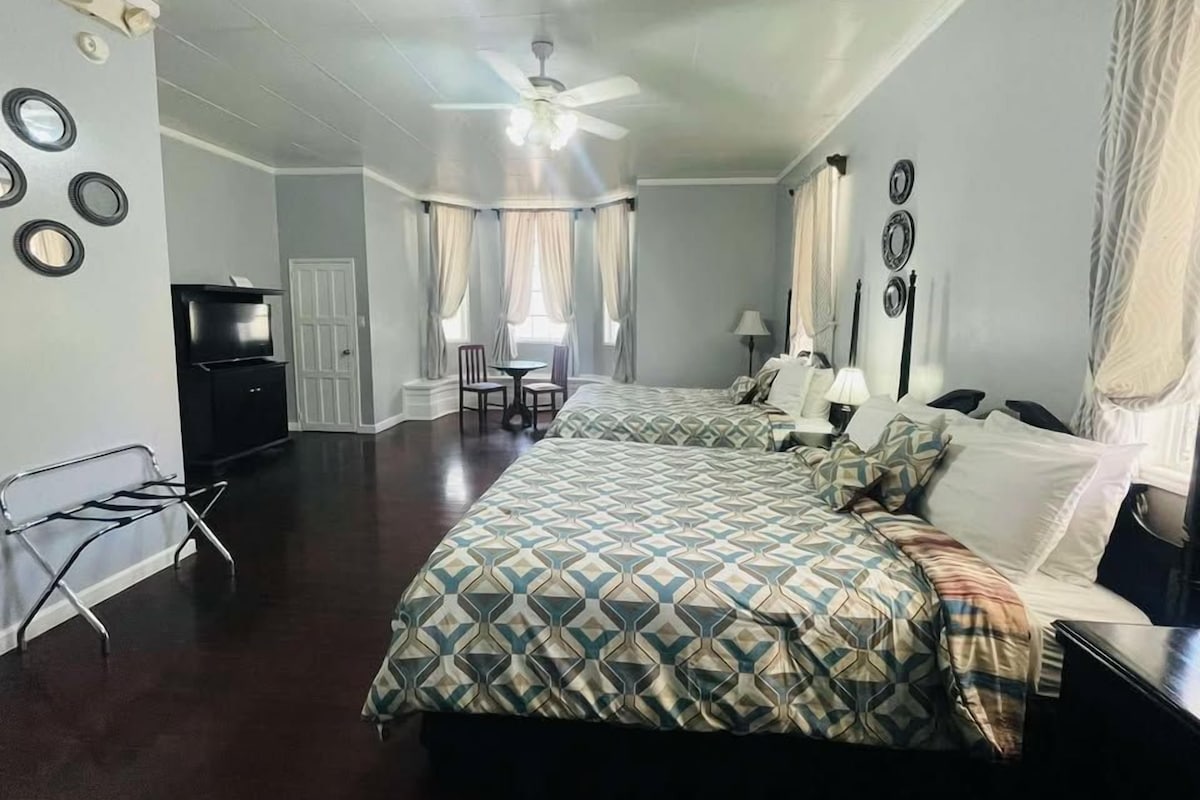 A hotel room with two beds, a TV, a desk, and a chair.