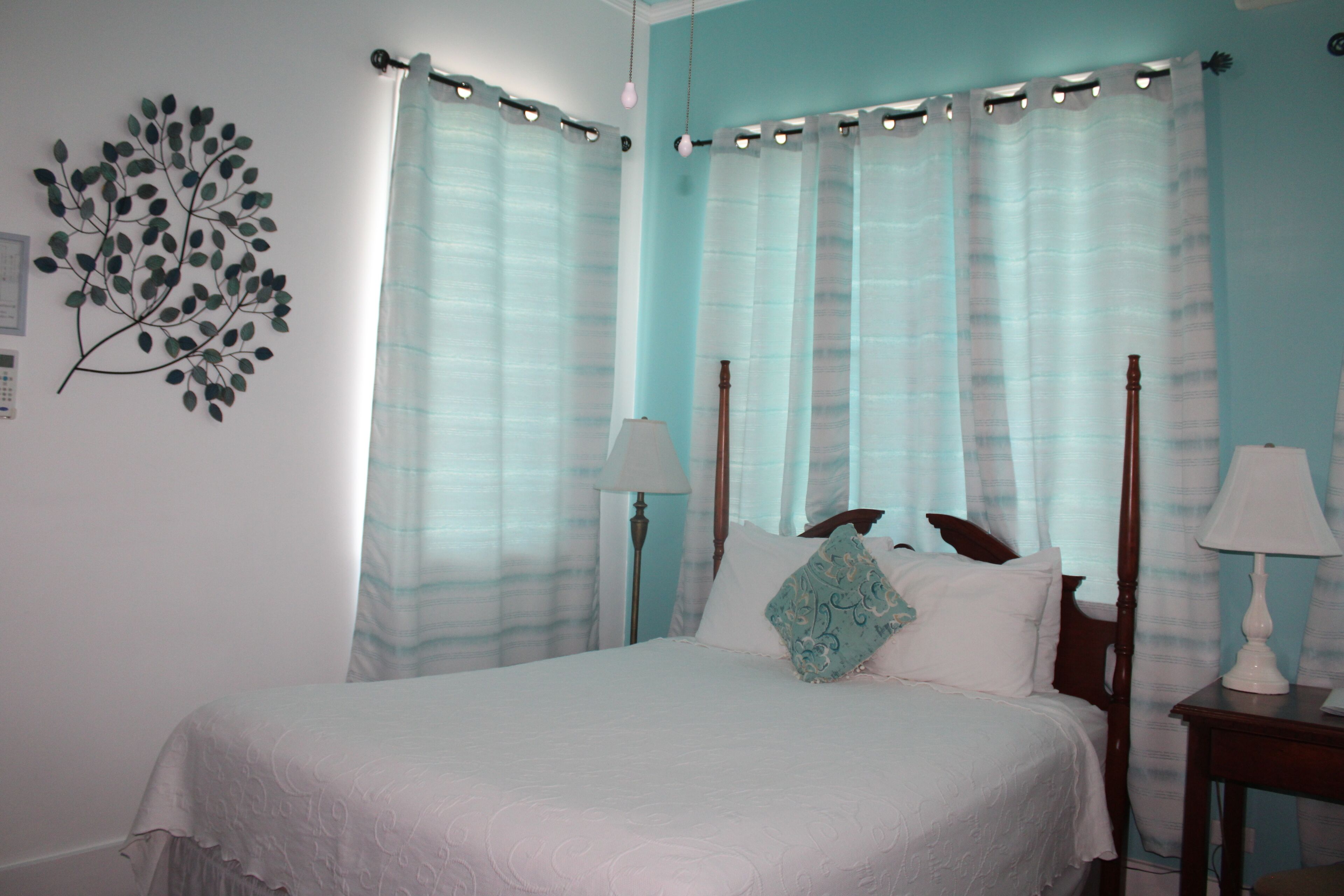A neatly made bed with white linens, a wooden headboard, and two bedside lamps.