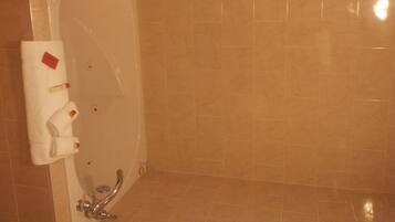 A bathroom with a bathtub, a towel rack with towels, and a shower area.