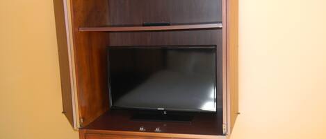 Un meuble de rangement en bois pour appareils multimédias, doté d’un téléviseur à écran plat, de deux tiroirs et d’une étagère située au-dessus du téléviseur.