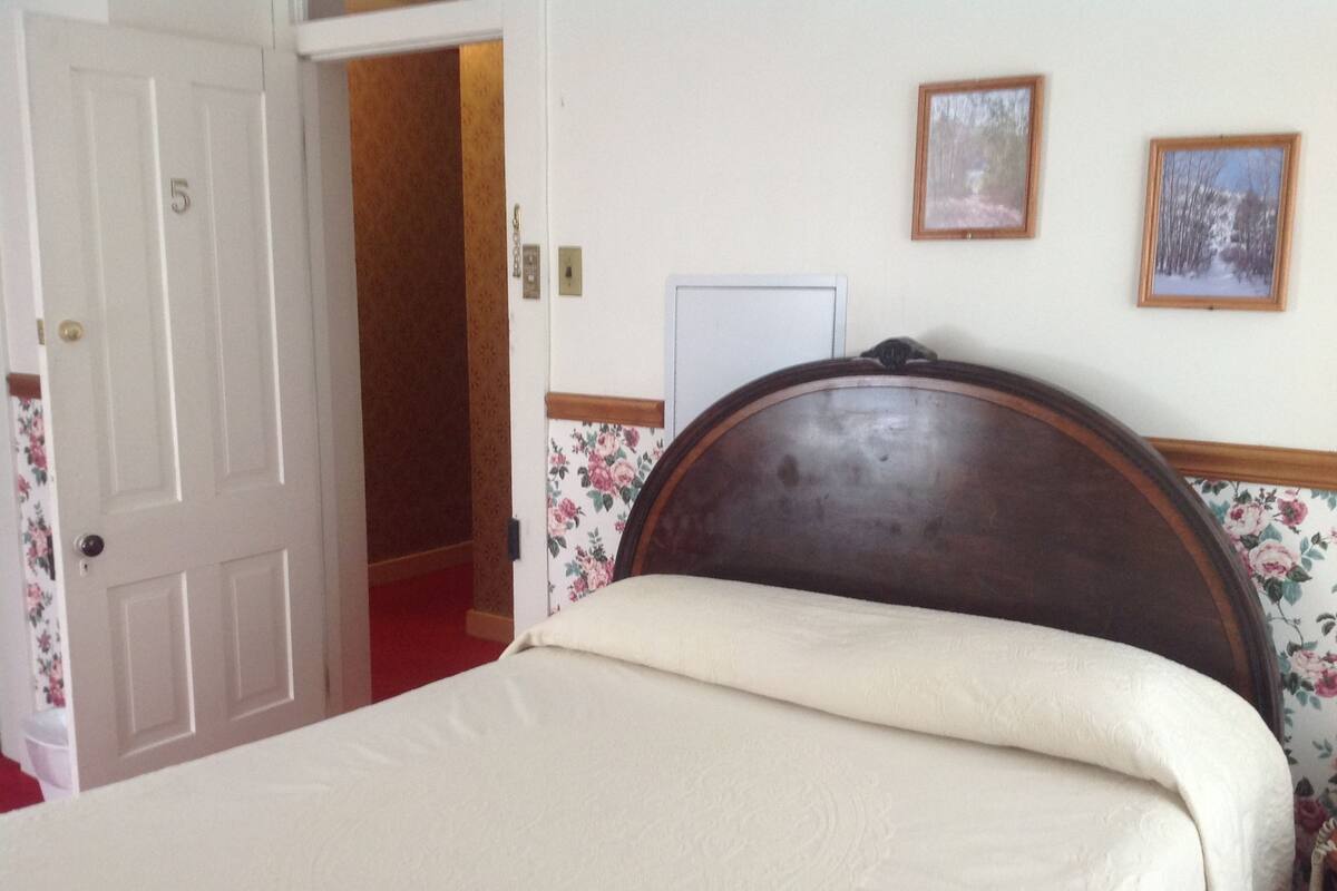 A room with a bed, a door, and a wall with two framed pictures.