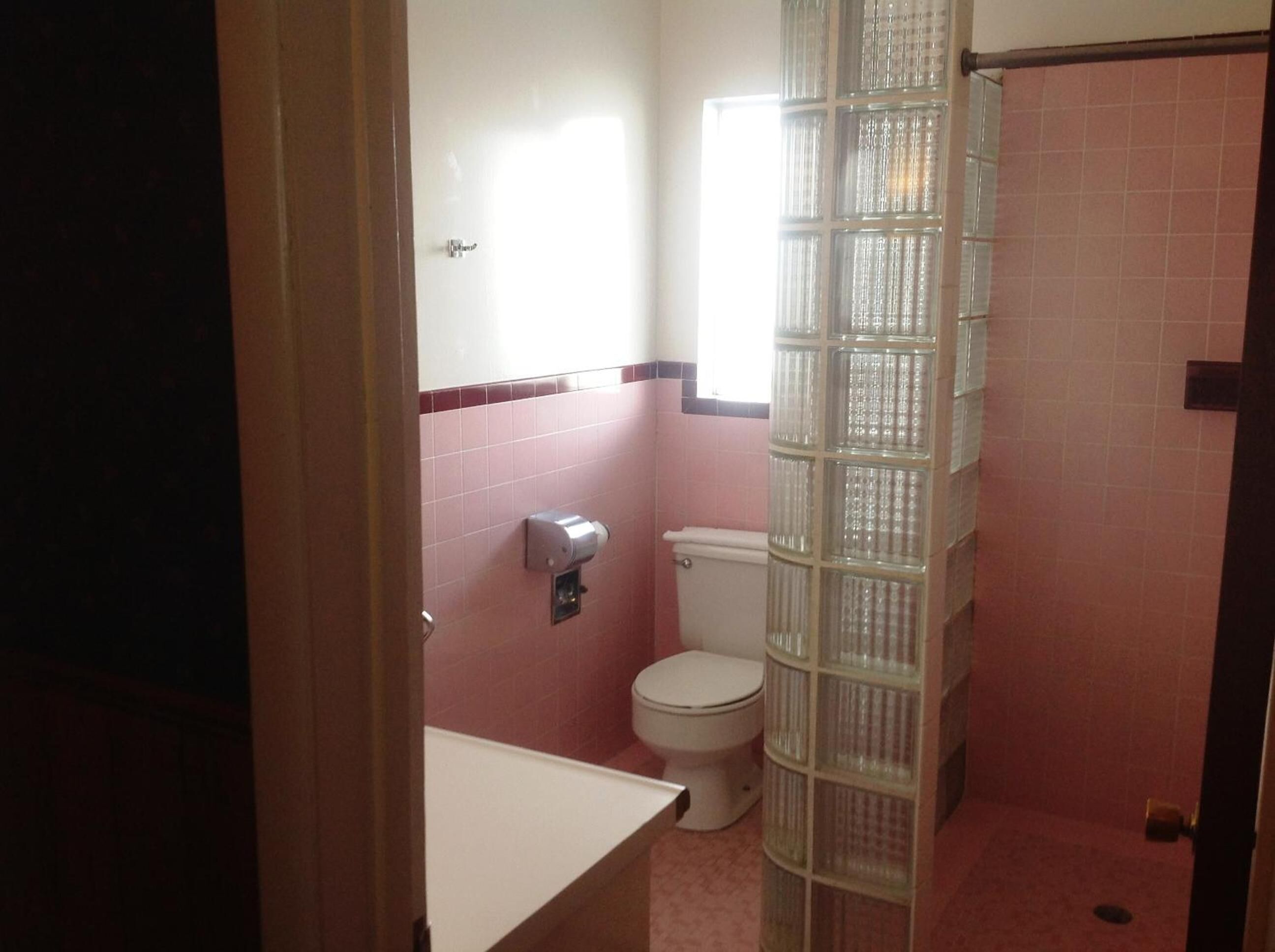 Un baño con inodoro, secamanos y cabina de ducha de vidrio.